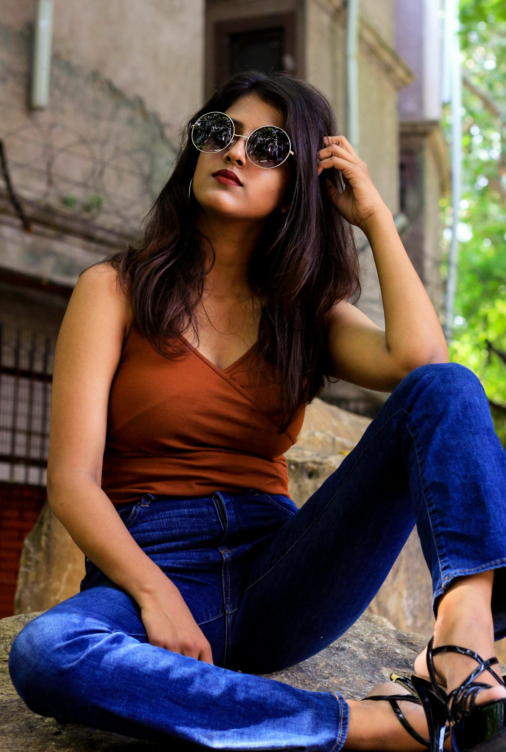 Fashionable woman in trendy sunglasses and denim, posing confidently outdoors.
