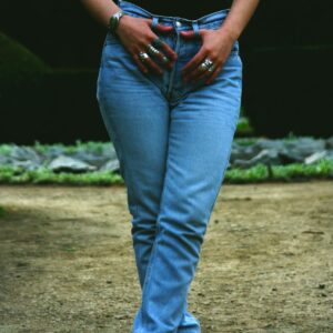 Stylish woman posing outdoors in blue jeans and boots, showcasing modern casual fashion.